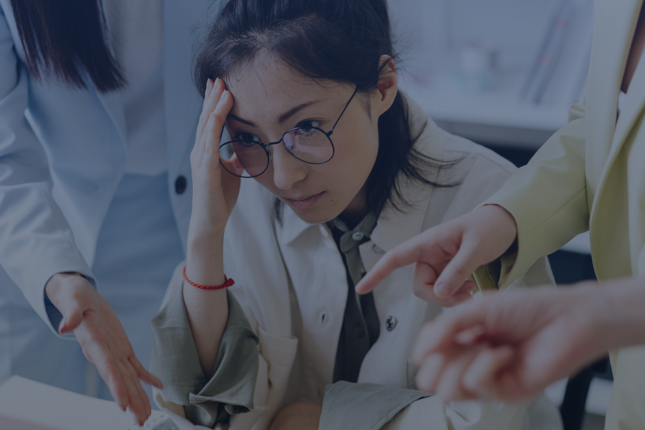 Tired woman with coworkers discussing a project in the office at a laptop, expressing frustration.