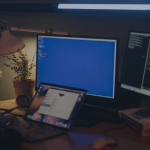 Woman using multiple screens for cybersecurity tasks in a cosy home office