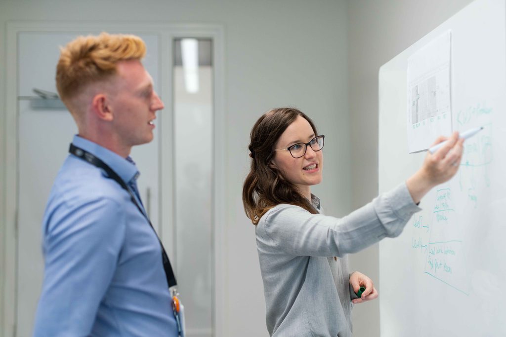Two colleagues consulting over an office whiteboard. What are you trying to achieve with your IT strategy?