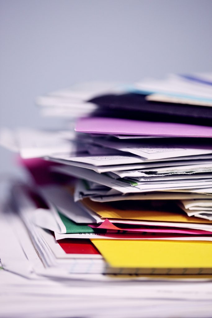 A large stack of colourful folders and documents - Cyber Essentials Plus certification is more than a paperwork exercise, it actively tests your security controls