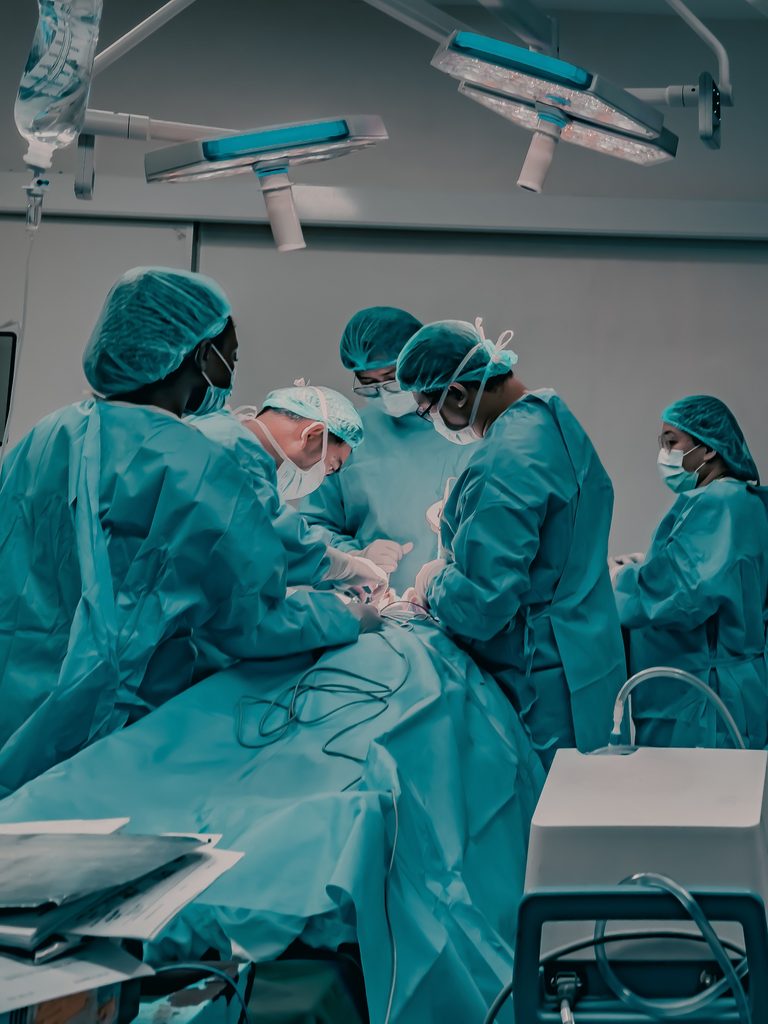 Medical professionals in scrubs performing surgery in a hospital operating theatre, one of the public sector settings suppliers serve through G-Cloud 15
