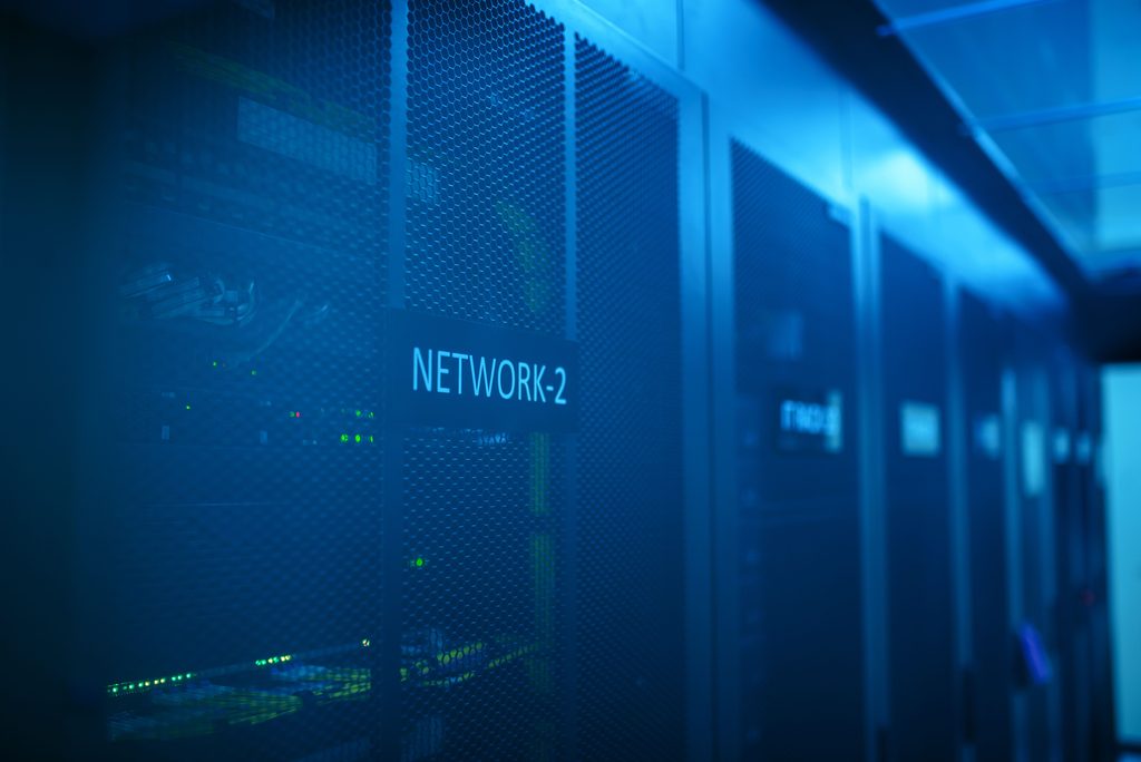 Rows of server racks in a blue-lit data centre, representing MOD supplier cyber security and managed infrastructure for defence suppliers