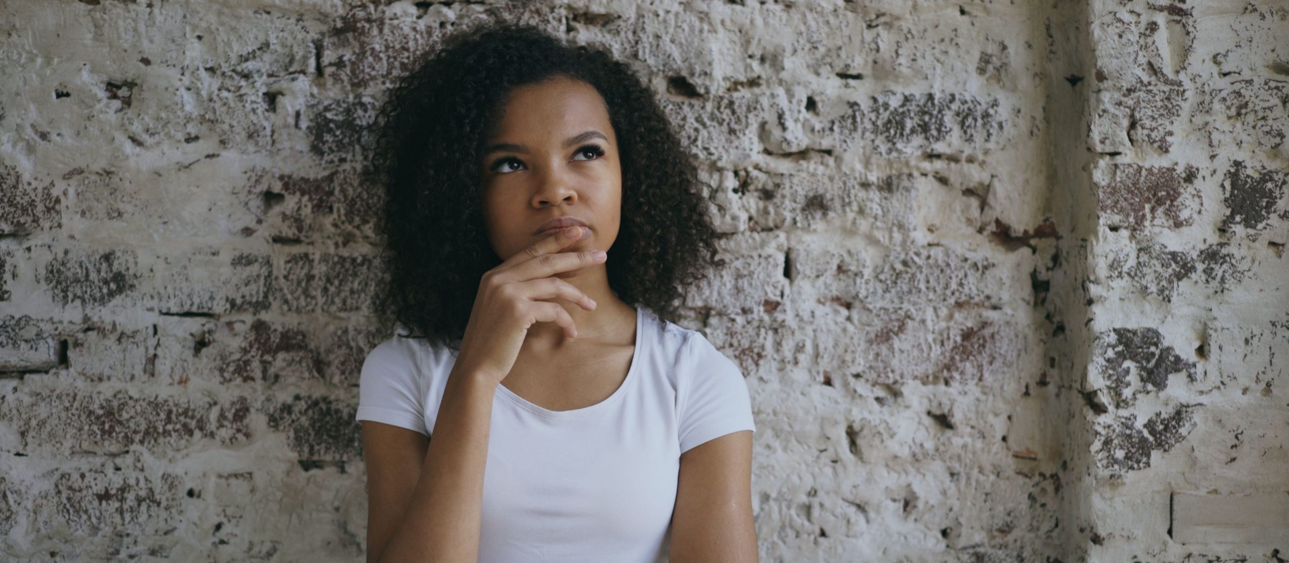 A woman in a thoughtful contemplative pose - good IT strategy consulting starts with asking the right questions about your business before choosing technology